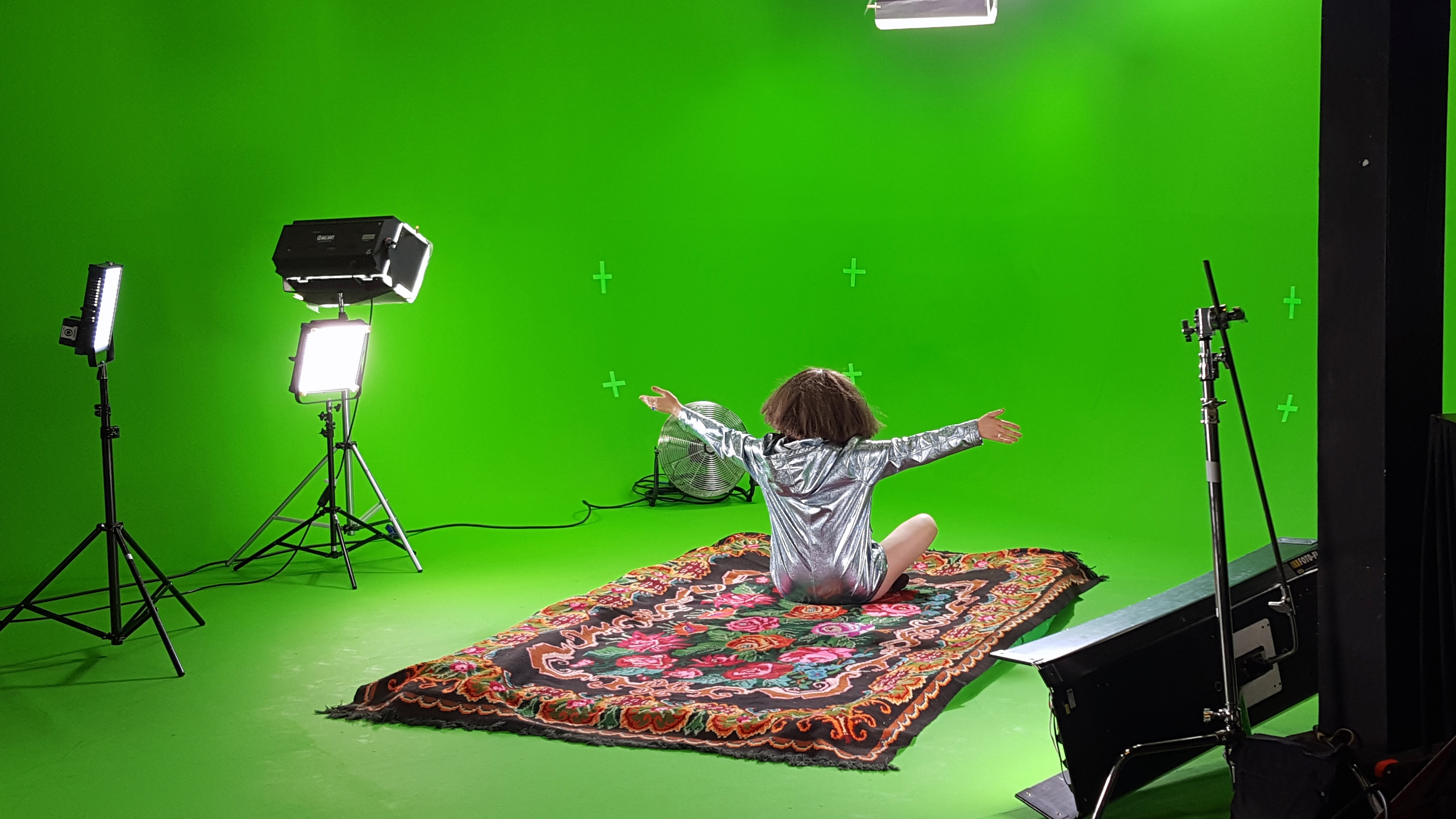 person sitting on a carpet on a greenscreen recording studio