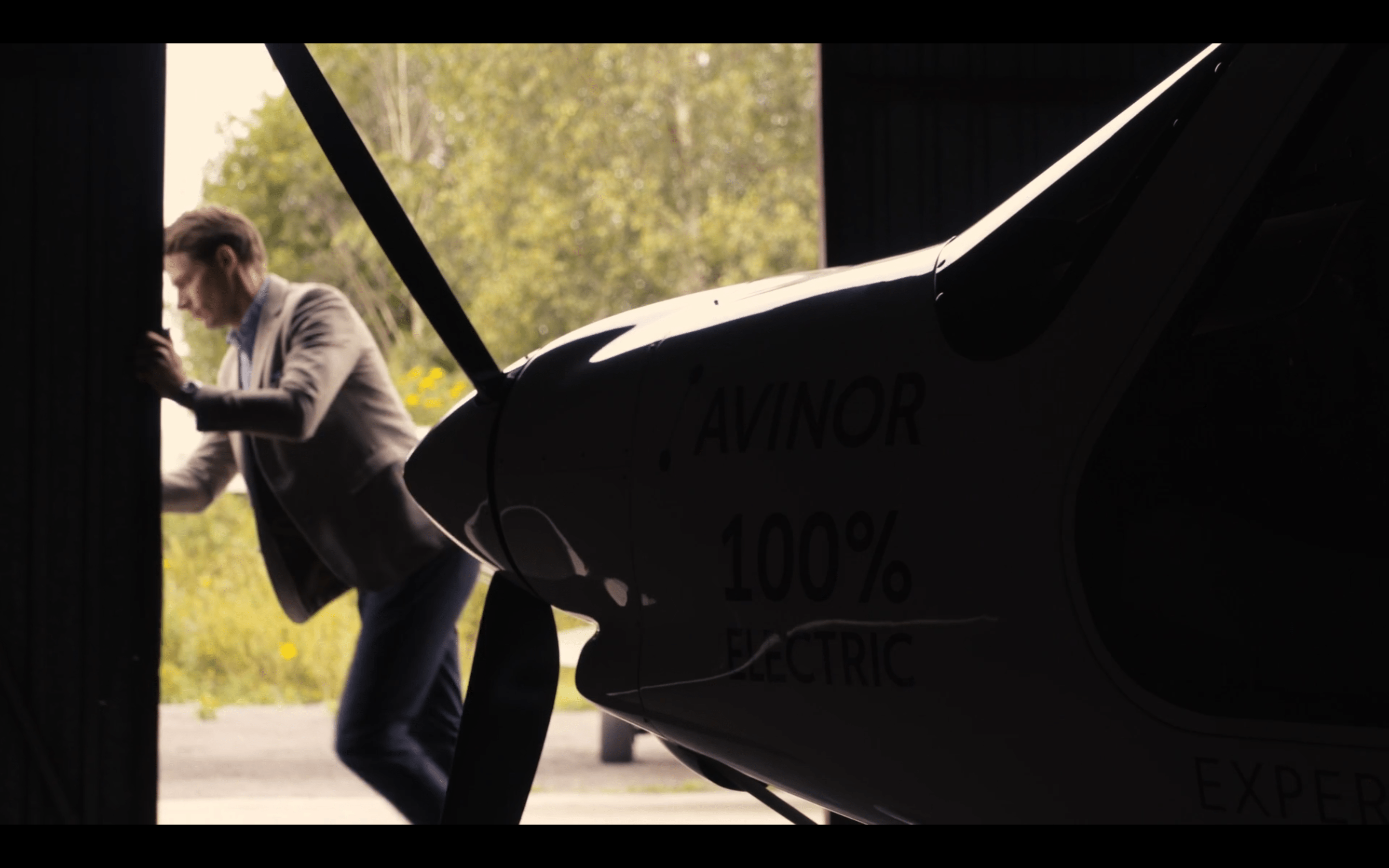 Person opening the door to a hangar, front of a plane in view
