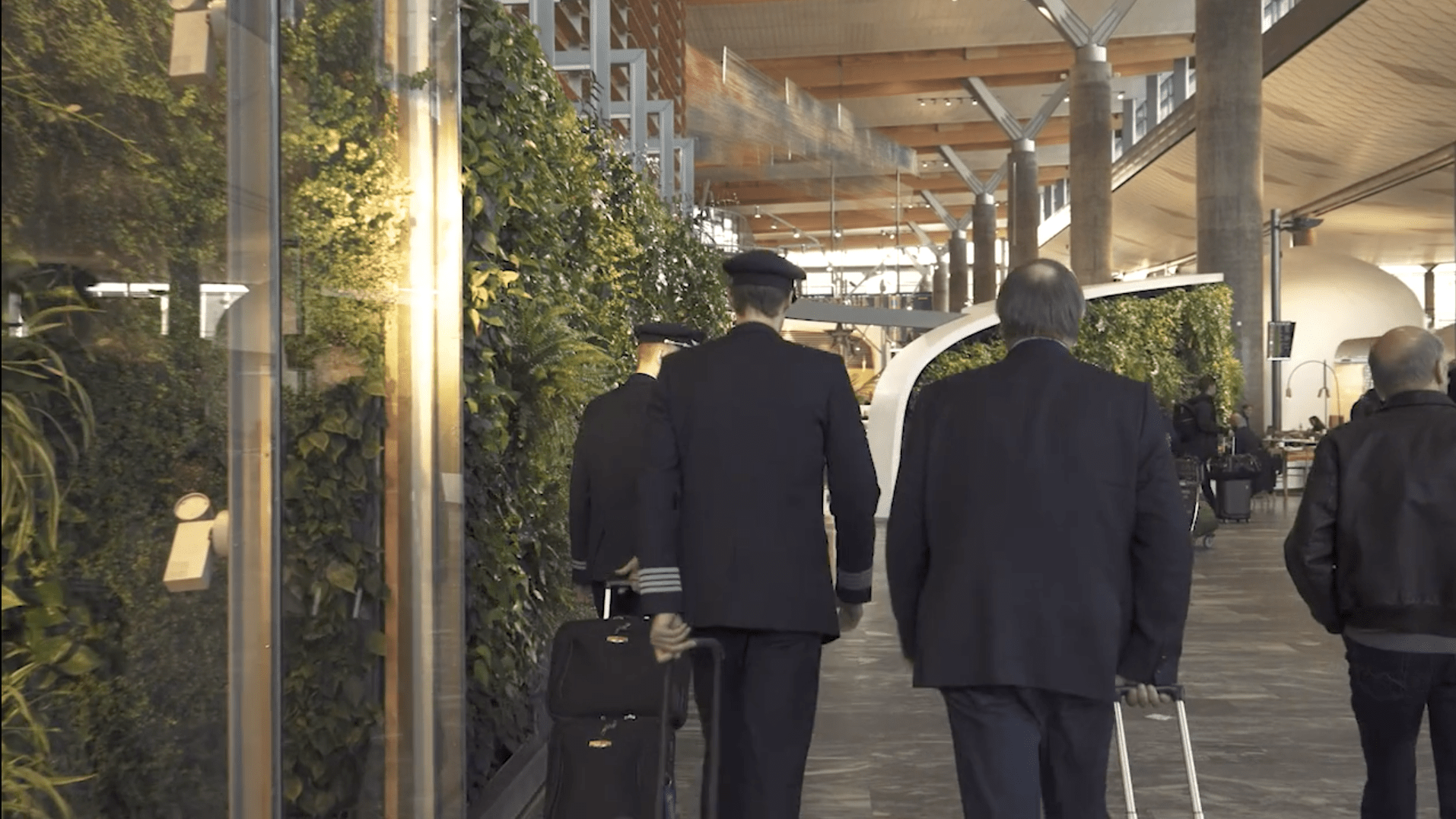 video screenshot of people with suitcases walking through a hallway